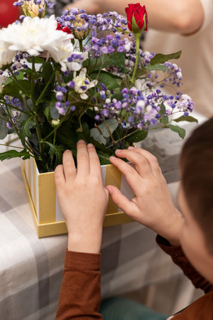 A child makes a handicraft with his own hands for Mother's Day. Boy making a bouquet for his mother. High quality photoの写真素材