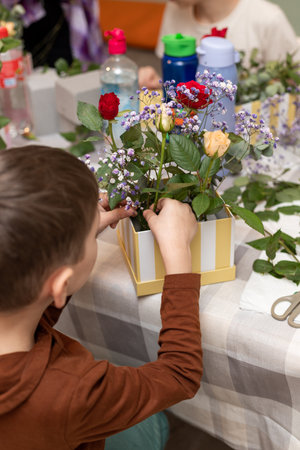 A child makes a handicraft with his own hands for Mother's Day. Boy making a bouquet for his mother. High quality photoの写真素材