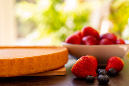 Sponge cake on the table. The process of making strawberry pie. Strawberries and blueberries on the table. High quality photoの写真素材