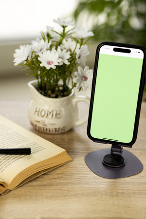 A mobile phone with a green screen. Smartphone on a stand. Book with a magnifying glass. High quality photoの写真素材