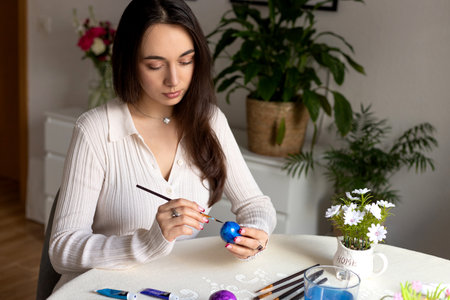 A beautiful woman is decorating Easter eggs. Dyeing Easter eggs at home. High quality photoの写真素材