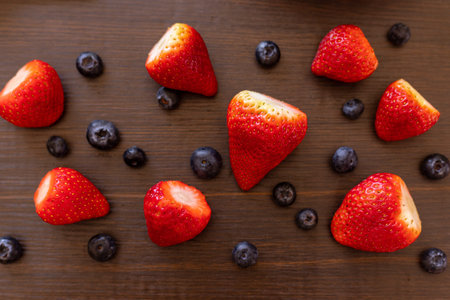 Berries in a plate. Berries on a wooden background. Strawberries and blueberries. Top view. High...