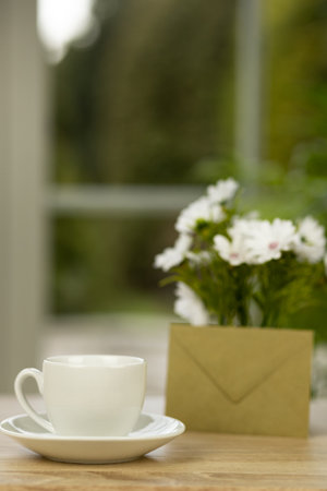 A cup of coffee, flowers and an envelope. Office desk with a cup of coffee. Desktop by the window. High quality photoの写真素材