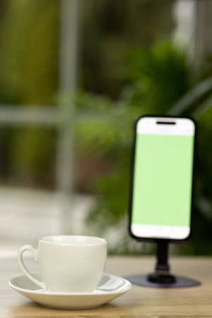 A cup of coffee and a smartphone. Smartphone on a stand. Chroma key. Coffee break. High quality photoの写真素材