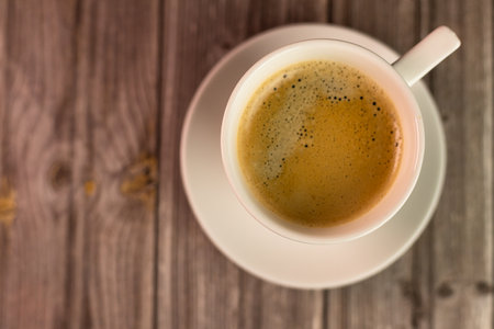 A cup of coffee on a wooden table. View from above. Coffee with foam. High quality photoの写真素材