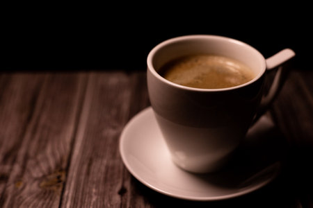 Aromatic strong coffee on the table. White Cup with Coffee on a Black Background. High quality photoの写真素材