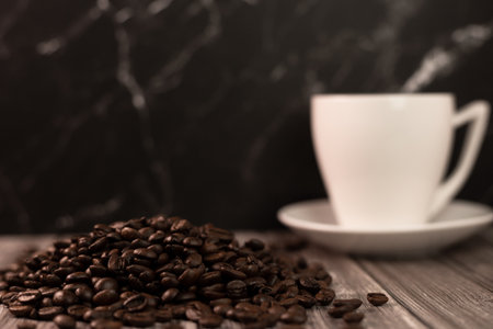 A cup of coffee and coffee beans on a dark background. Roasted coffee beans. High quality photoの写真素材