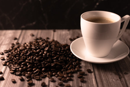 A cup of coffee and coffee beans on a dark background. Roasted coffee beans. High quality photoの写真素材