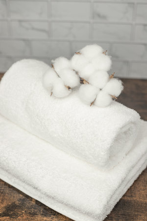 White terry towels are beautifully folded. Cotton flowers on towels. Top view. High quality photoの写真素材