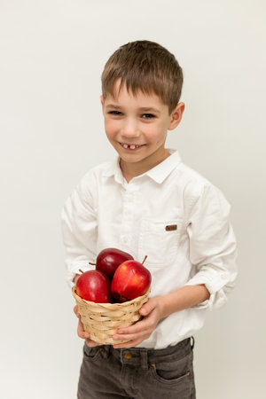 A boy holds a basket of red apples on a white background. Boy with apples. High quality photoの写真素材
