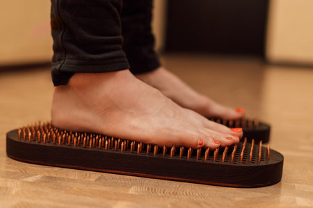 Women's feet on a Sadhu board. Therapy on a board with nails. High quality photoの写真素材
