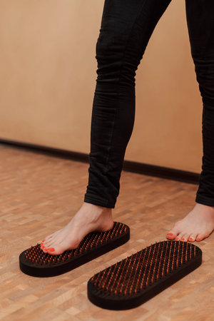 A woman tries to stand on the board of a sadhu. An attempt to stand on nails. Women's legs. High quality photoの写真素材