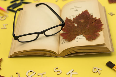 Autumn dried maple leaf, open book and reading glasses. Nostalgia. Autumn backgroundの写真素材