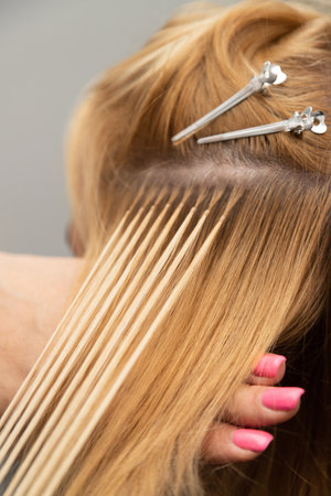 Hair extension process with blonde strands close-upの写真素材