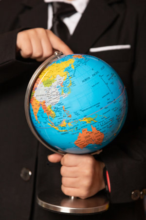 A close-up of a boy's hand on a globe. The boy is holding a globe. Close-up. High quality photoの写真素材