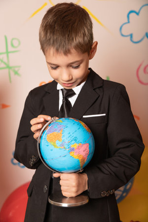 Geography lesson. A globe in the hands of a student. The boy is looking at the globe. High quality photoの写真素材