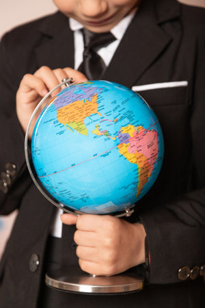 Geography lesson. A globe in the hands of a student. The boy is looking at the globe. High quality photoの写真素材