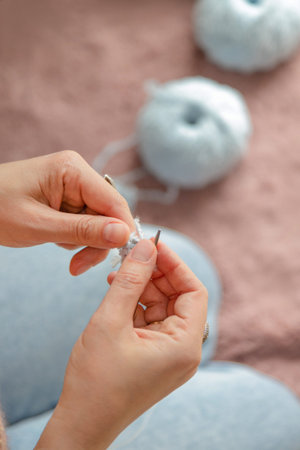 A woman sits on the floor and knits. Women's hands with knitting close-up. High quality photo
