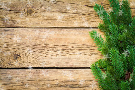 Christmas background with fir tree branches and snowflakes on a rustic boardの写真素材