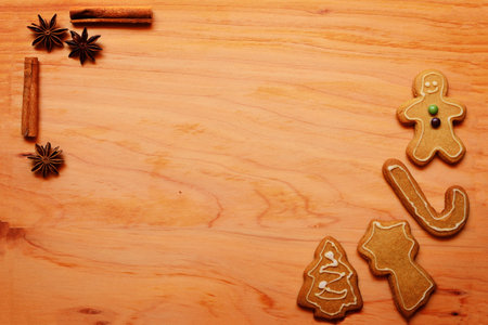 Festive background with gingerbread cookies and spices arranged on a wooden board. Corners...