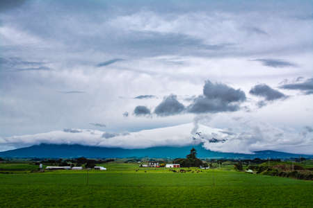 A glimpse of Mount Taranaki through heavy clouds on gloomy winter day.の写真素材