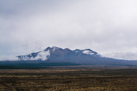 Magnificent Mount Ruapehu partially obscured by low clouds. Desolated high land field in Central Plateau of New Zealand. Desert Road, North Island, New Zealandの写真素材