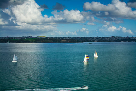 Sailing boats racing over calm waters of Auckland Harbour on a beautiful winter day. North Island, New Zealandの写真素材