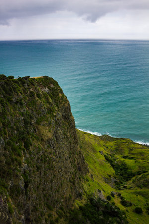 Narrow promontory rising high above over calm blue waters of Tasman Sea. Te Toto Gorge Lookout, Raglan, New Zealandの写真素材