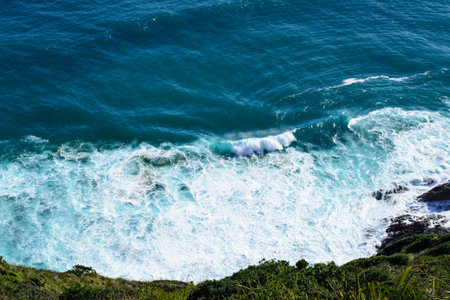 Aerial view of a giant ocean wave onto the shore. Top down photo of turquoise sea water surface....
