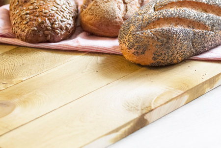 Beautiful golden bread with sunflower seeds and poppy seeds on a pink towel