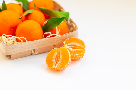 Tangerines with leaves in a beautiful basket isolated on whiteの写真素材