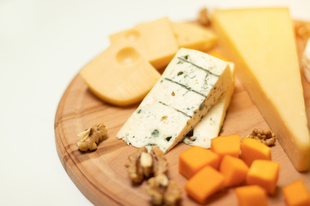 Delicious cheese on a wooden round boardの写真素材