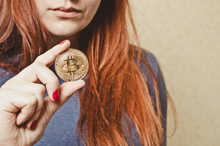 A woman holds a gold coin in her hands bitcoinの写真素材