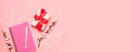 Flat lay composition with empty notebook and gift decoration white flowers on pink.の写真素材