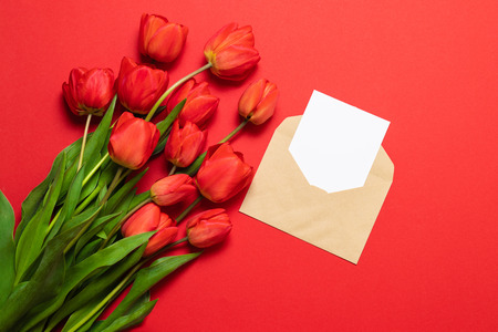 Top view of red tulips and craft envelope with a letter, flat lay, top viewの写真素材