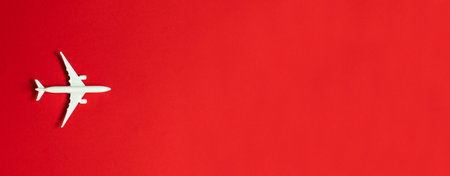 Flat lay design. Airplane toy model in white on a red background with space for text.の写真素材