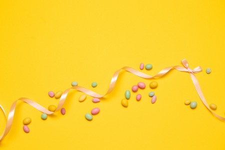 Colorful candy are scattered on yellow background.の写真素材