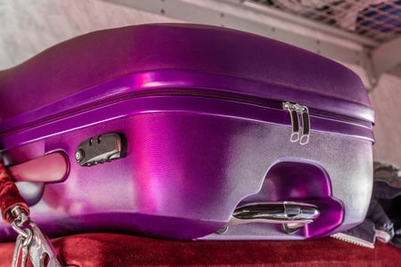 Lilac Polycarbonate suitcase on the shelf in the train carの写真素材
