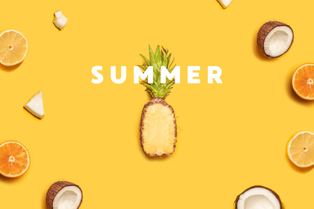 Creative summer composition of tropical fruit juices on a yellow background: oranges, coconuts, lemons, pineapples.の写真素材