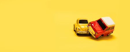 Transportation concept. Accident 2 toy yellow and red cars on a yellow monophonic background. Close...