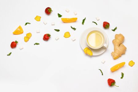 Flat lay concept of glass cup of tea and fresh strawberries, pieces of ginger, orange, mint and sugar on a gray background. Flat lay, top view.の写真素材