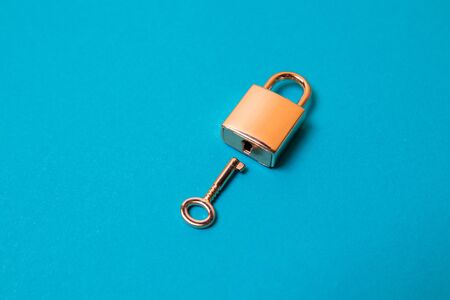 Flat lay protection concept. Locked padlock and key on the blue background.の写真素材