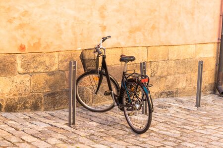 Black bike parked against yellow wall in the street of Stockholm. Old city summertimeの写真素材