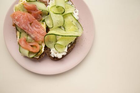 Sandwich with salmon, cucumber, cheese and rye bread close-up on white background. Diet and obesity conceptの写真素材