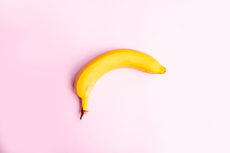 Summer minimalist concept. Flat composition of banana on pink background with copy space for your text.の写真素材