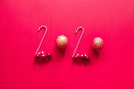 Christmas composition with 2020 number made with various Christmas cone candy, red balls on red background. Flat lay, top view, copy spaceの写真素材