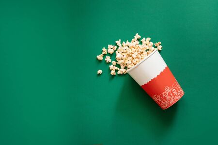 Top view of popcorn in paper bag on green background top view copy space. Unhealthy diet concept.の写真素材