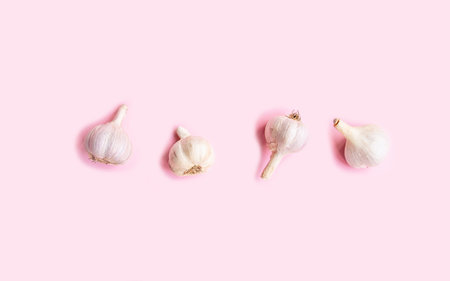 Flat lay composition with fresh garlic on light pink background