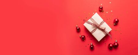 Creative composition of gift box with gold stars decoration, balls on red background. Flat lay, top view, copy spaceの写真素材