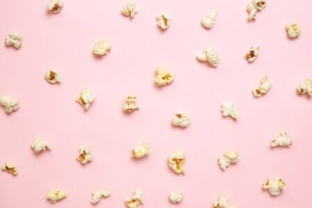 Cinema, movies and entertainment concept. Top view of tasty salted popcorn pattern on a pink background. Woman with paper bucket of popcornの写真素材